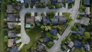 Overhead view of a suburban neighborhood of single-family homes around a cul-de-sac, with tree-lined yards and a backyard pool