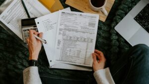 Tax forms, a calculator and a pen on a desk while someone works through tax calculations